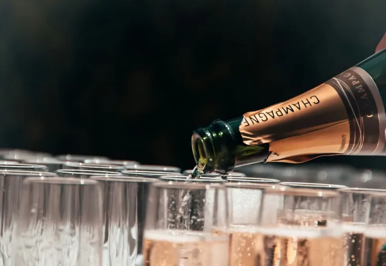 Une bouteille de champagne déverse son contenu dans une flûte sur fond noir.