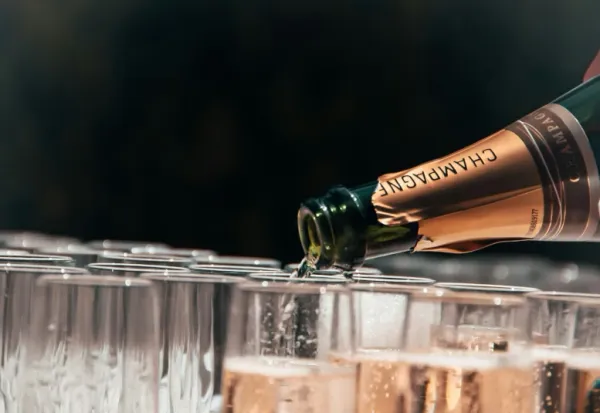 Une bouteille de champagne déverse son contenu dans une flûte sur fond noir.